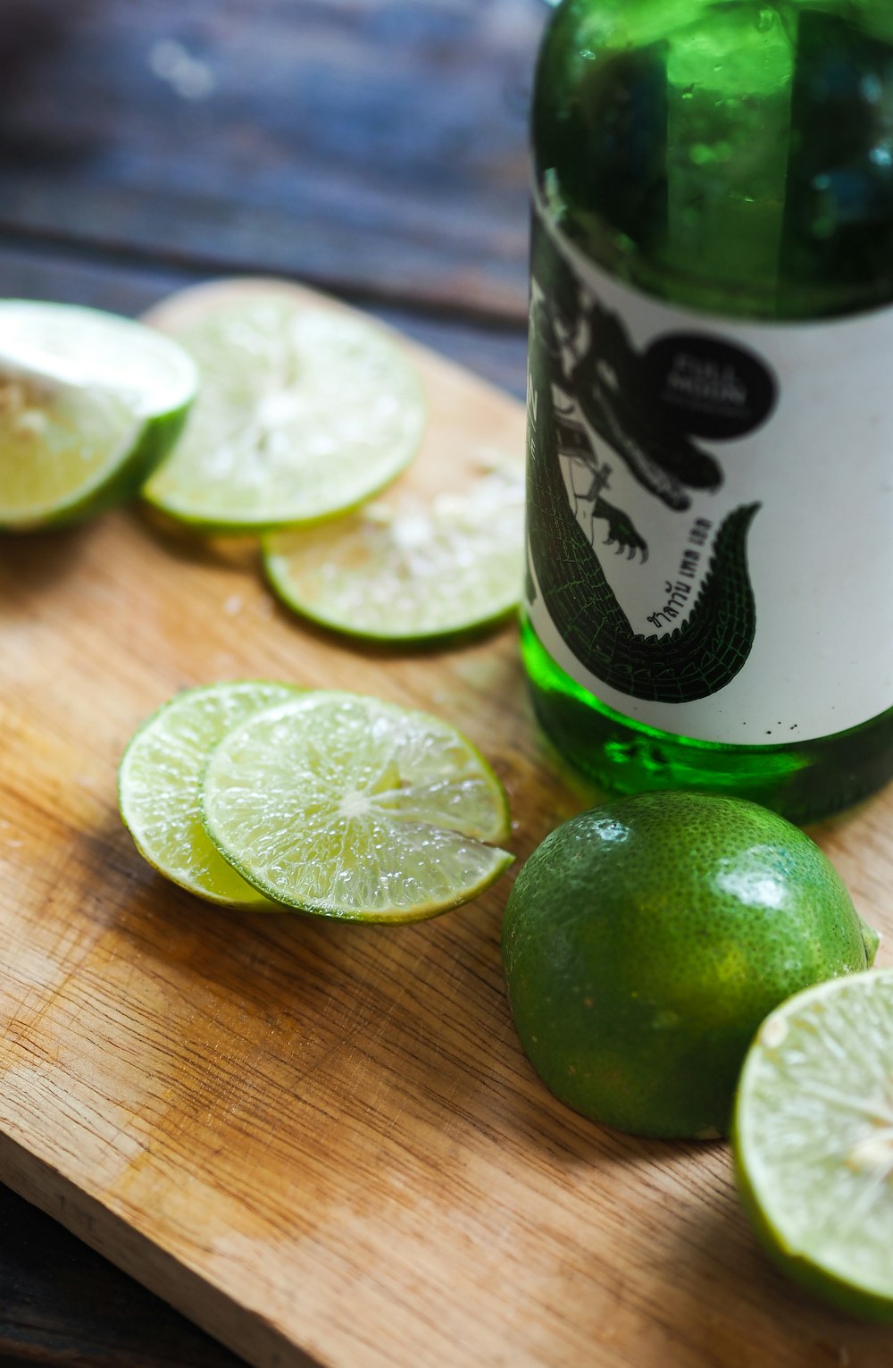 sliced limes near green glass bottle