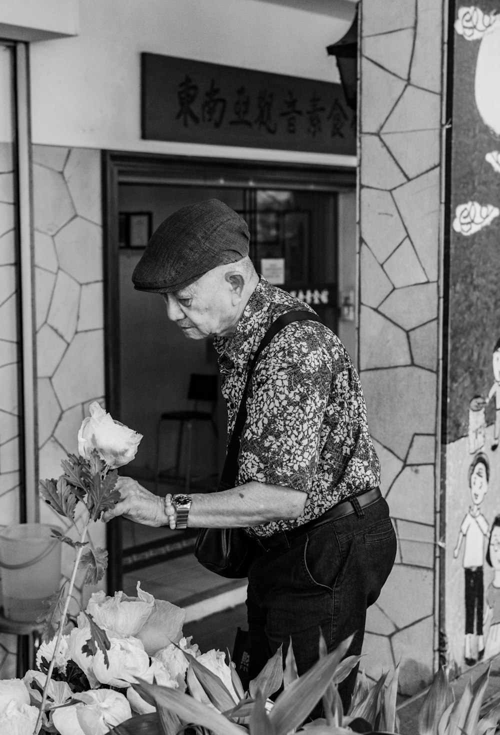 greyscale photo of man wearing flat cap