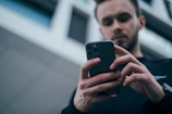 man wearing black sweater using smartphone