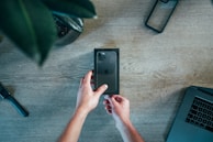 Close-up of hands comparing two popular gadgets side by side on a wooden table.