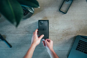 Close-up of hands comparing two popular gadgets side by side on a wooden table