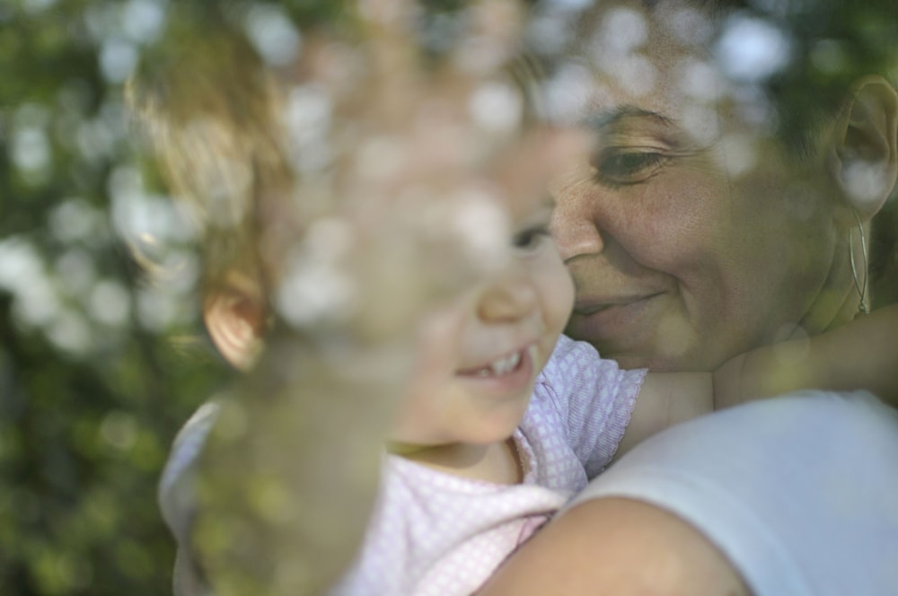 portrait of woman wearing white crew-neck shirt carrying baby