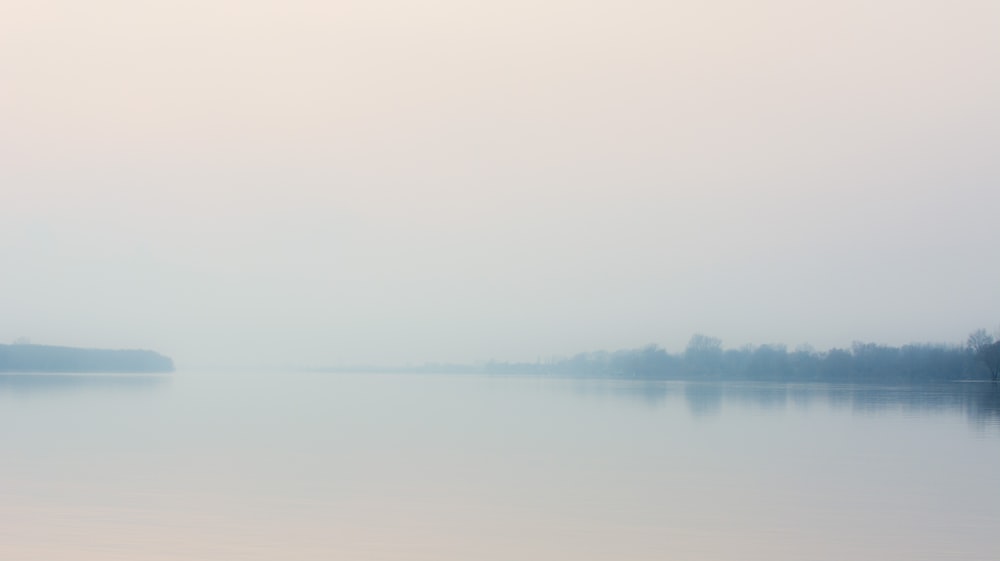 calm body of water under white sky