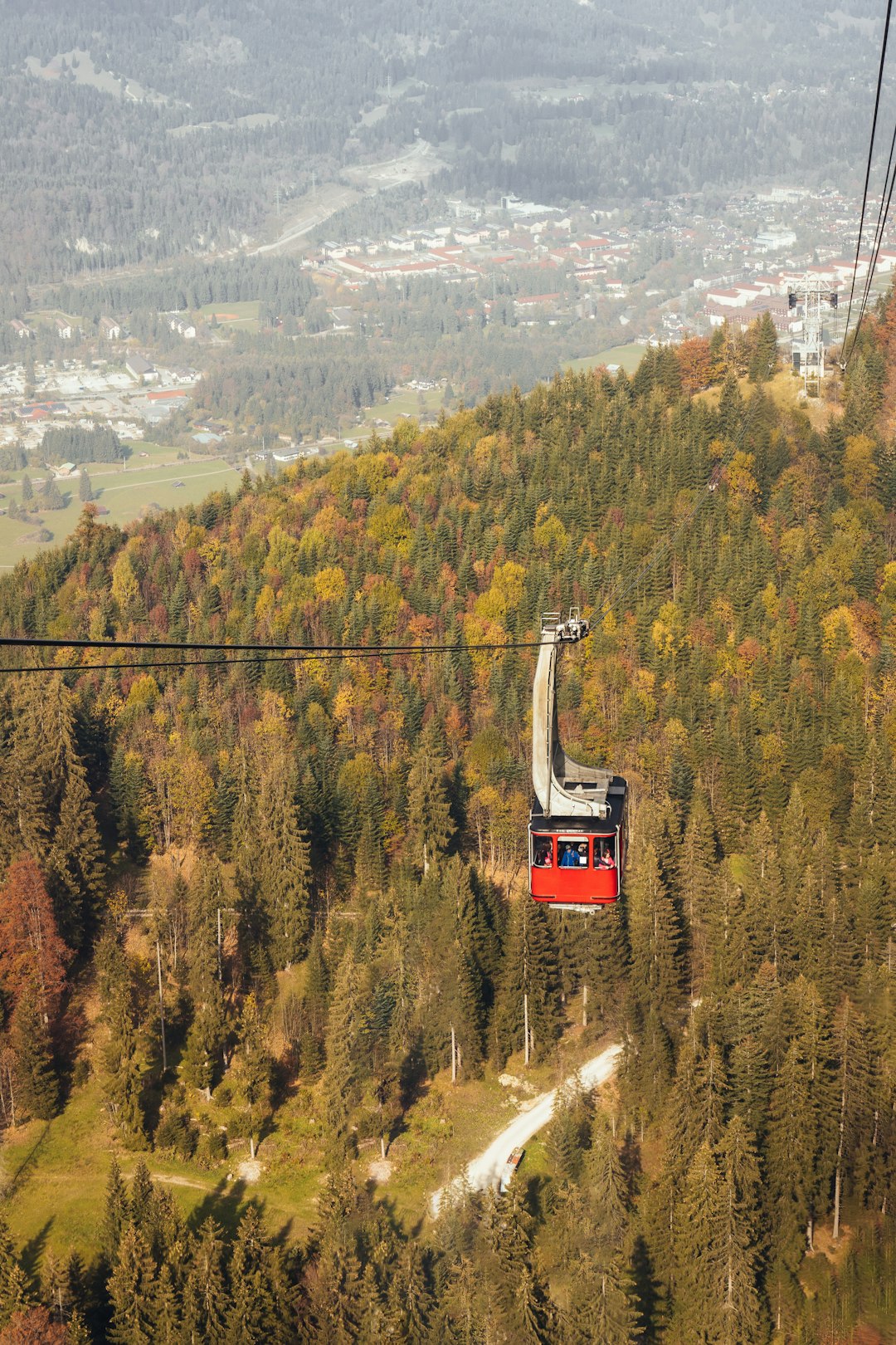 red cable car above trees during daytime
