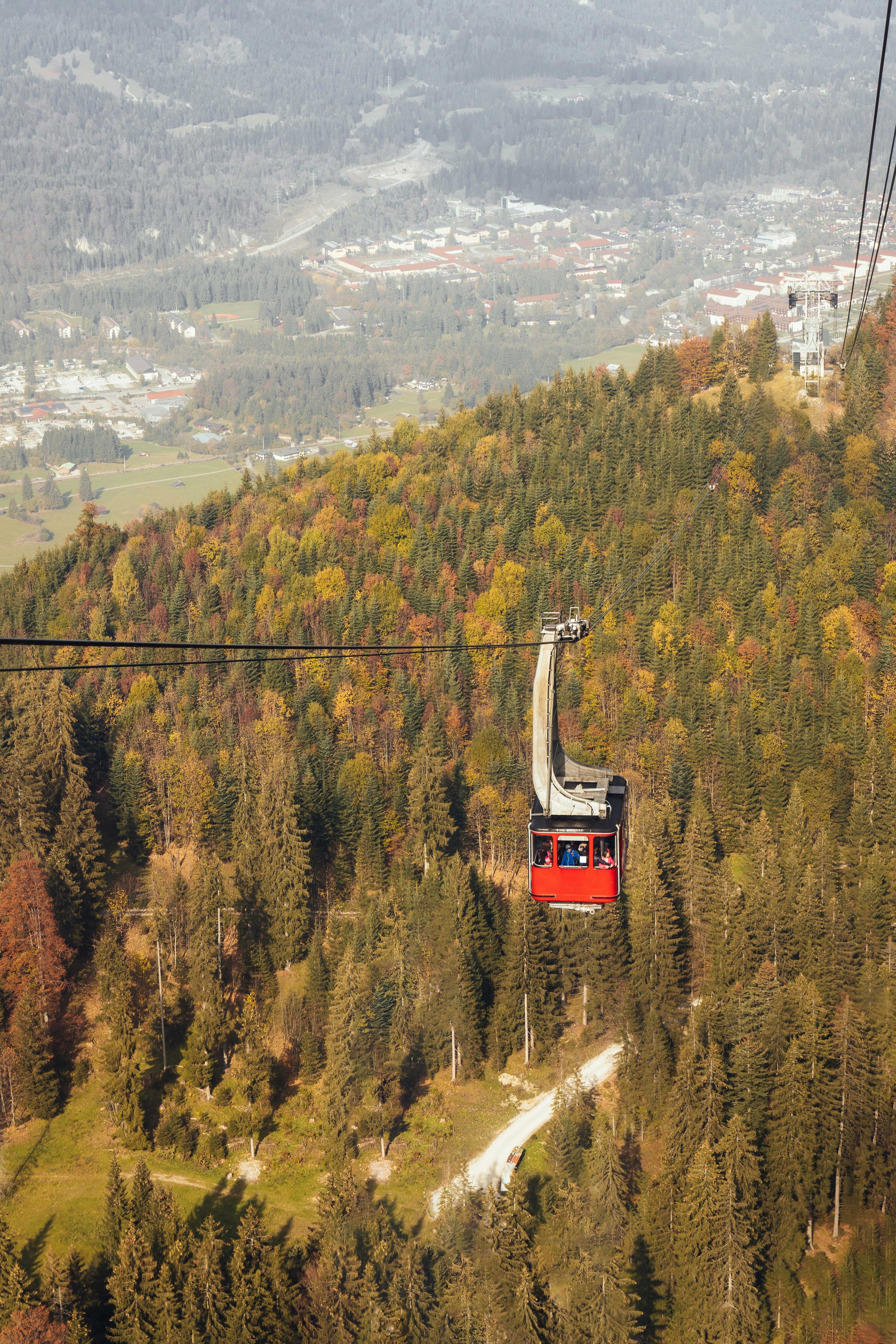 red cable car above trees during daytime