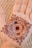 A beautifully intricate henna design is applied to the palm of a hand. The design consists of concentric circles with detailed paisley and floral patterns, featuring delicate lines and dots.