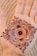 A beautifully intricate henna design is applied to the palm of a hand. The design consists of concentric circles with detailed paisley and floral patterns, featuring delicate lines and dots.