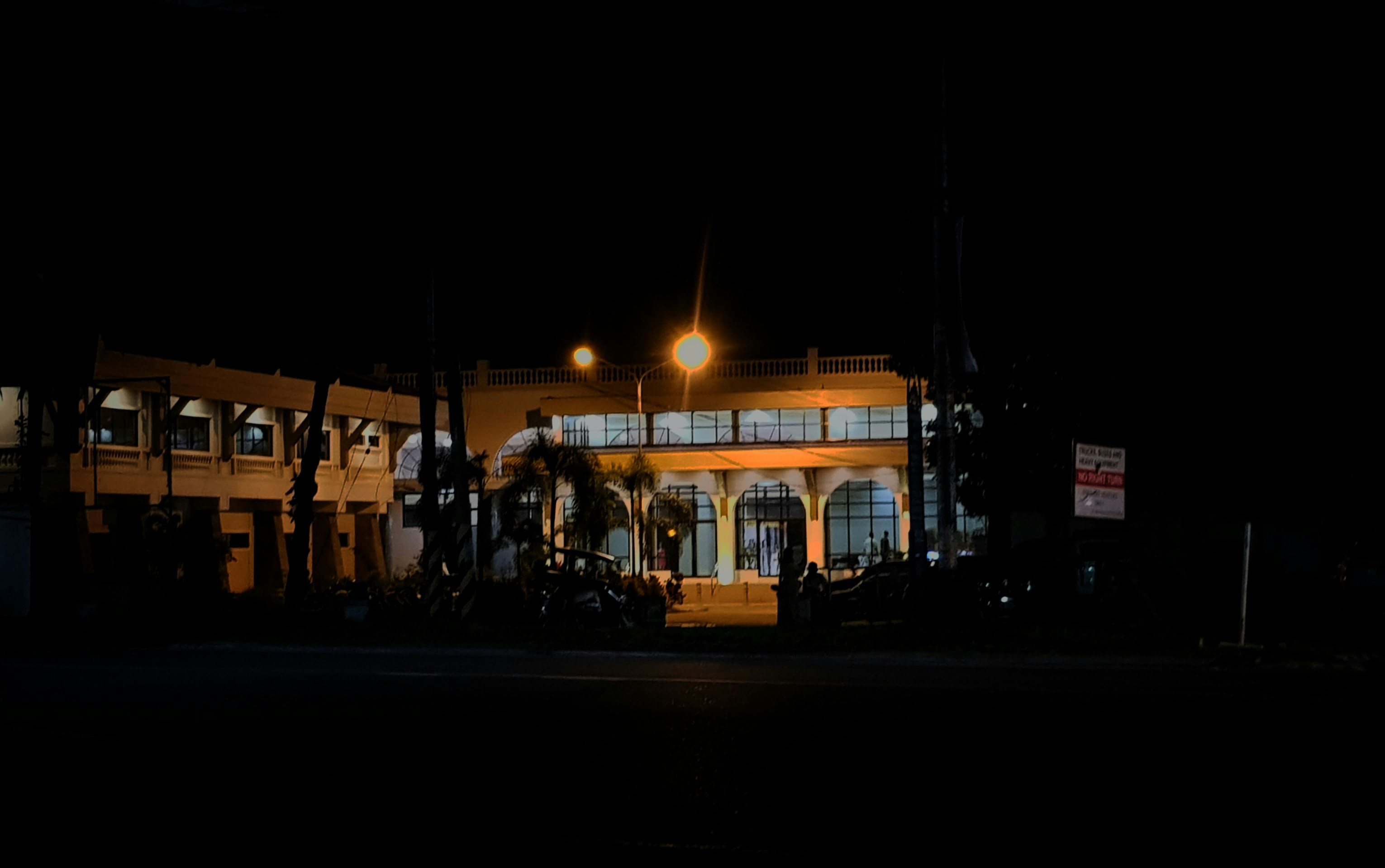 a building lit up at night with palm trees
