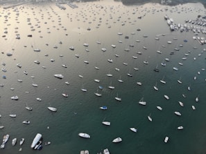 An aerial view of multiple vessels anchored near offshore oil platforms at sunset.