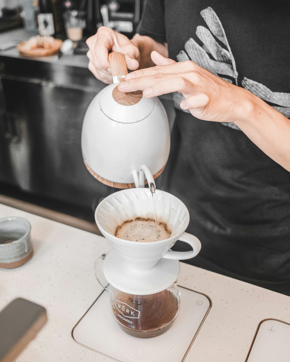 person pouring liquid on mug from teapot