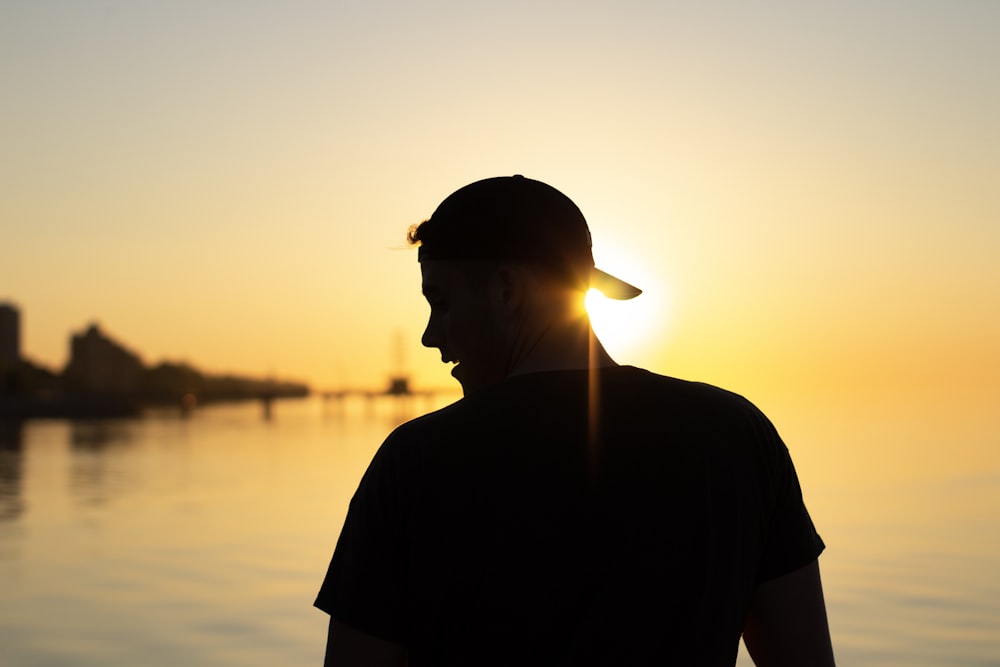 silhouette of man wearing cap during sunset