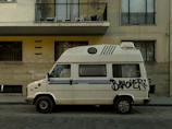 A polished white van with rauhous branding, parked in an urban setting.