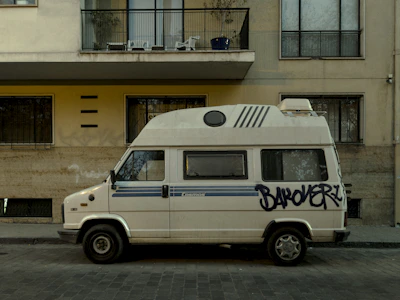 A polished white van with rauhous branding, parked in an urban setting.