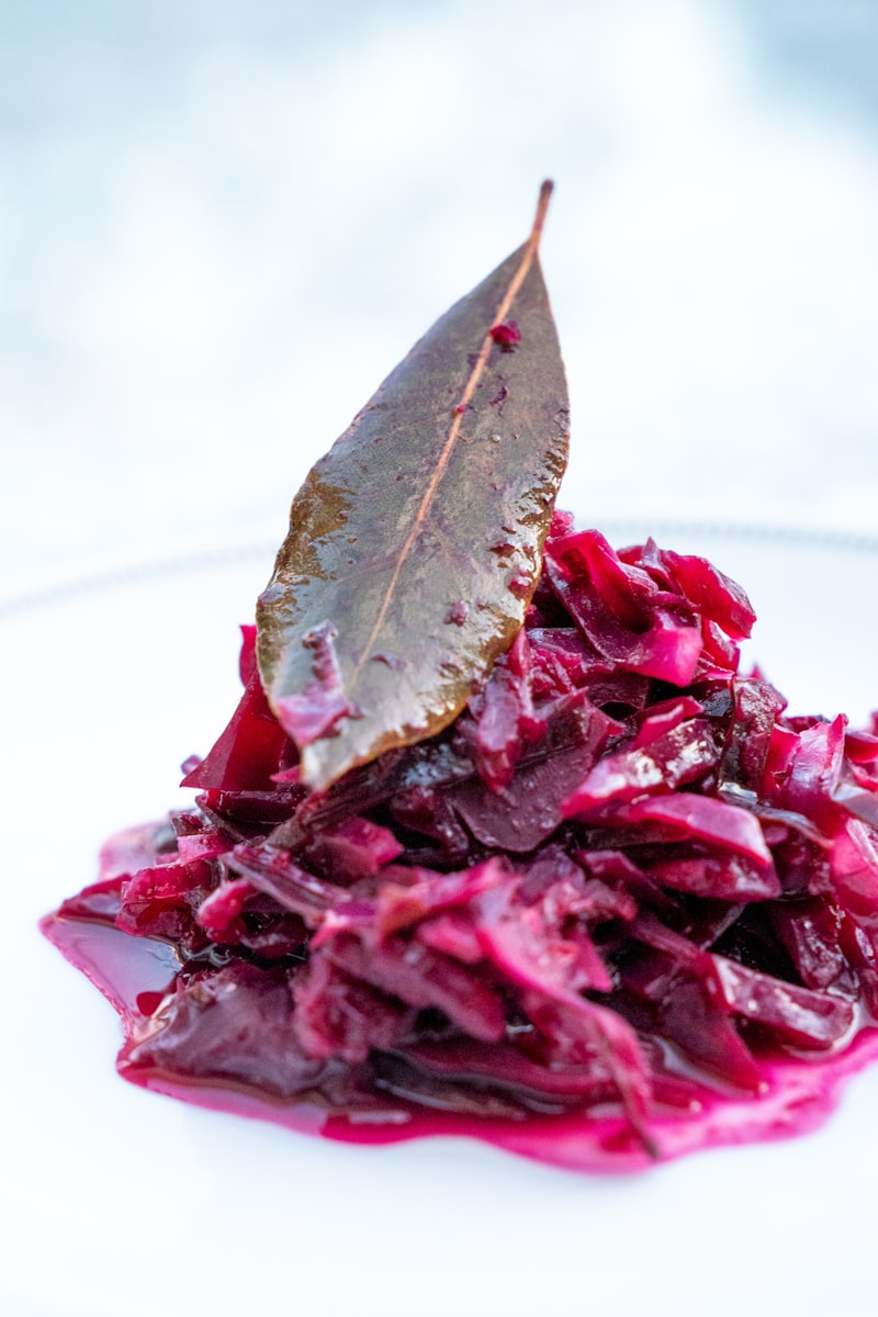 Braised red cabbage served on a white plate with a bay leaf
