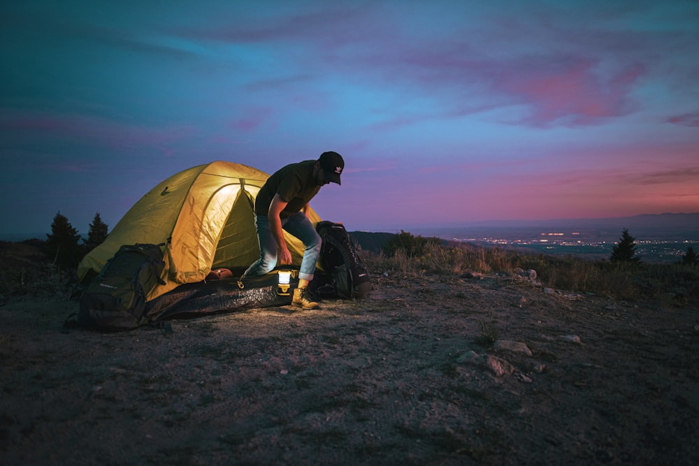 man standing beside dome tent outdoor during nighttime