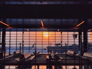 the sun is setting through the window of an airport