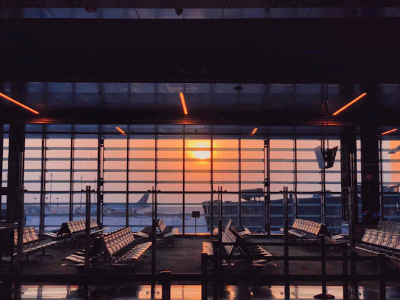 the sun is setting through the window of an airport