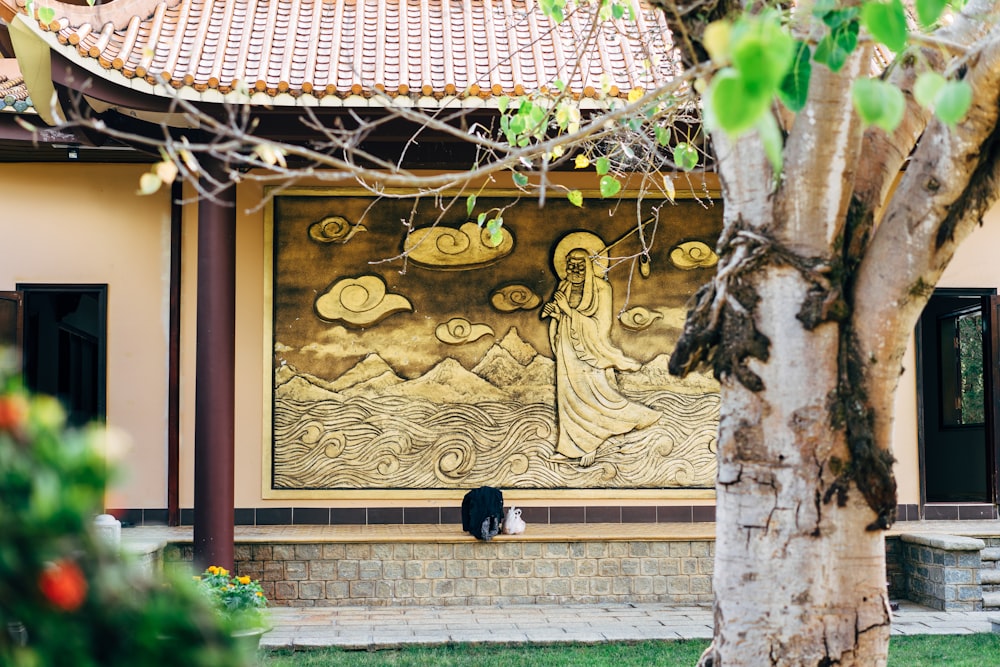 una pintura en el costado de un edificio junto a un árbol