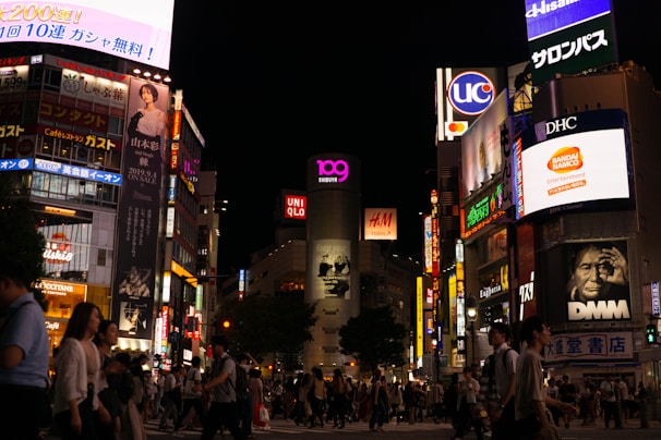 crowd of people walking beside buildings during nightime