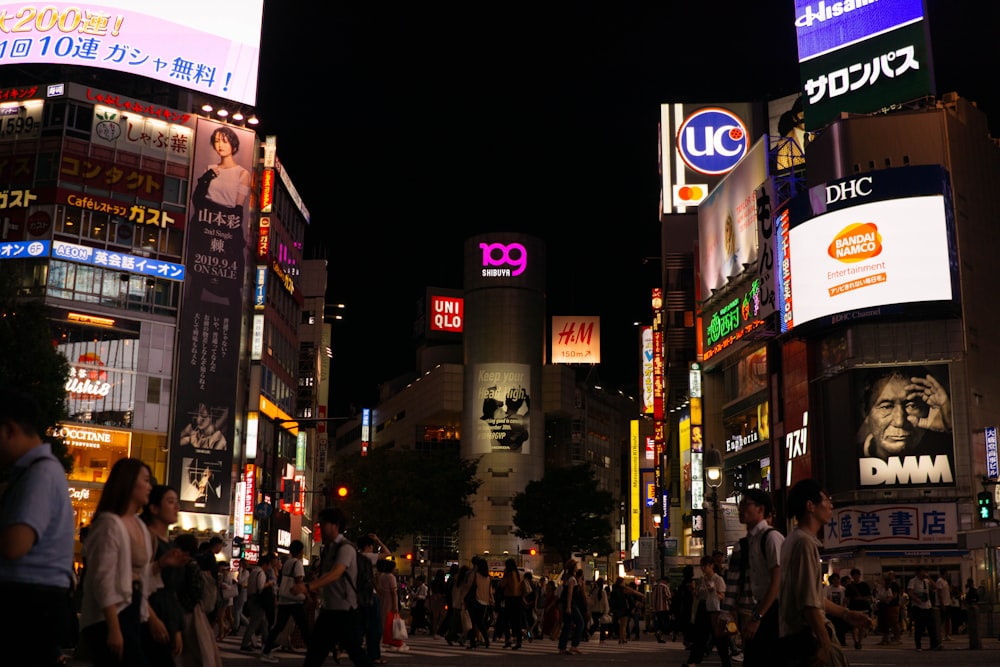 folla di persone che camminano accanto agli edifici durante la notte