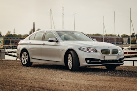 A sleek luxury sedan parked by a bustling international port.