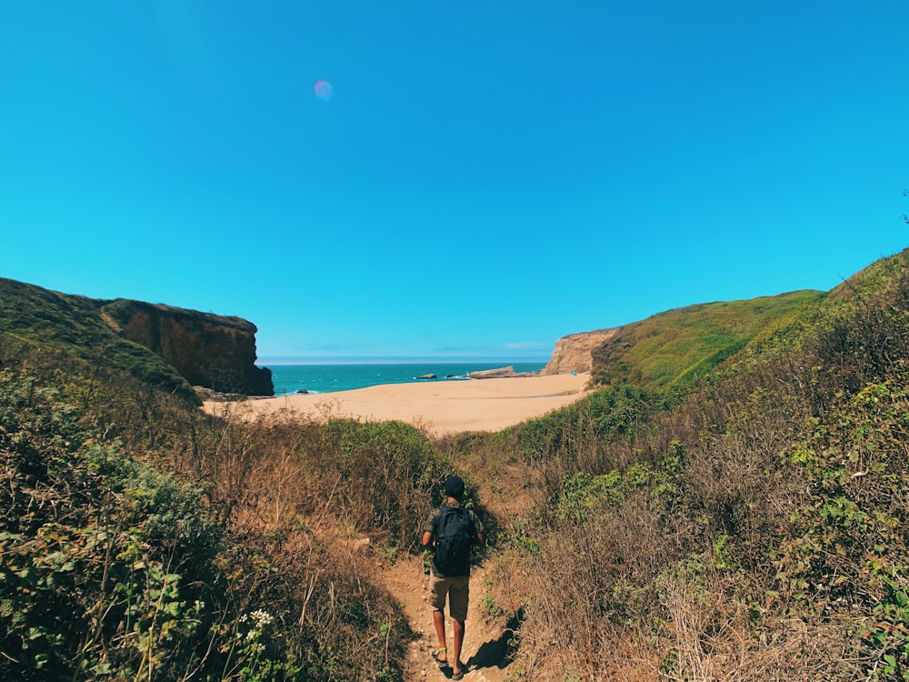 man walking on hill trail