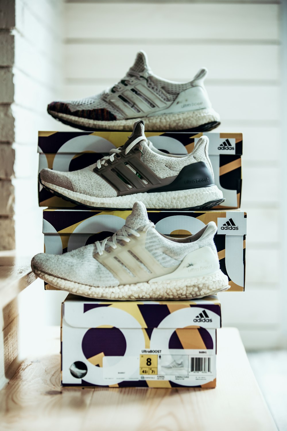three unpaired gray adidas running shoes with boxes