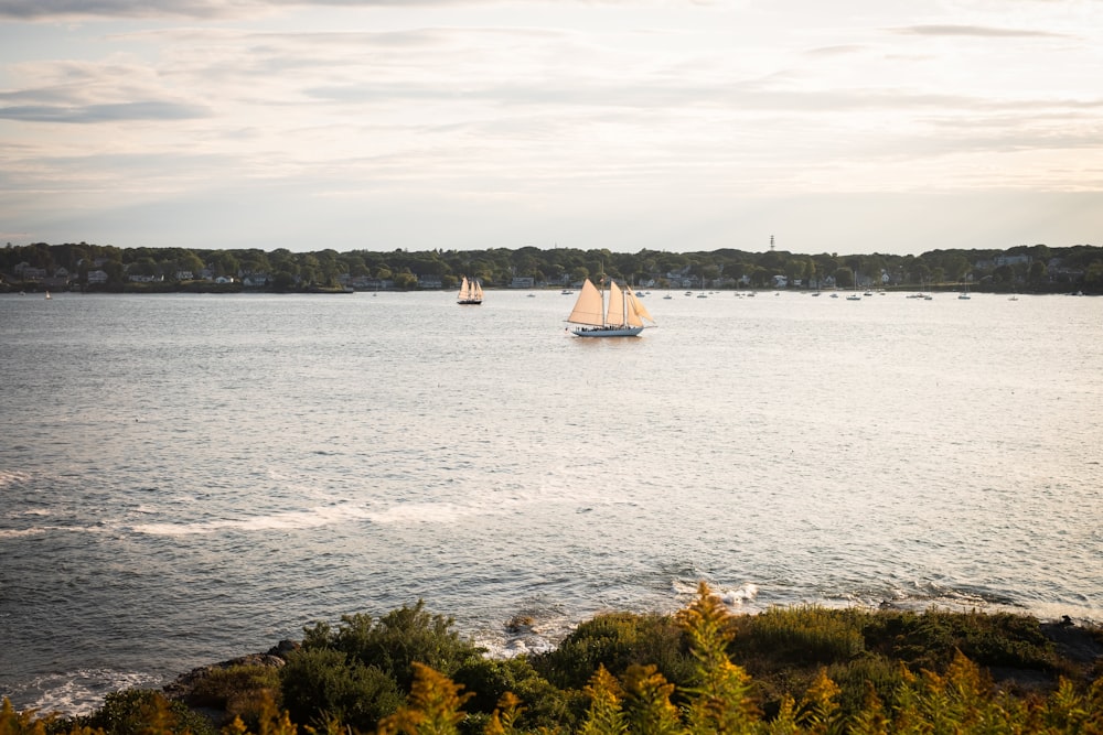 boats in body of water viewing mountain under white sky during daytime