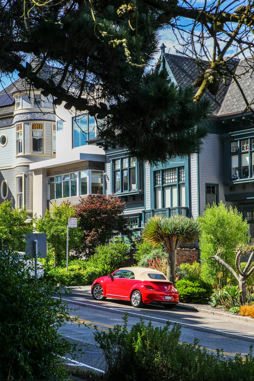 red coupe parking near house during daytime