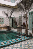 Sunlit courtyard with traditional Moroccan tiles and lush greenery at Riad Itry.