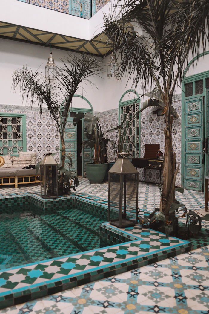 Courtyard plunge pool with teal zellige tiles and palm trees inside a Marrakech riad