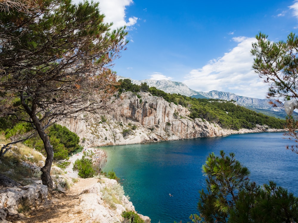 blue body of water viewing mountain under blue and white sky during daytime