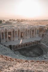 An outdoor cinema setup at dusk with red lighting highlighting ancient Sicilian ruins.