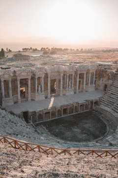 An outdoor cinema setup at dusk with red lighting highlighting ancient Sicilian ruins.