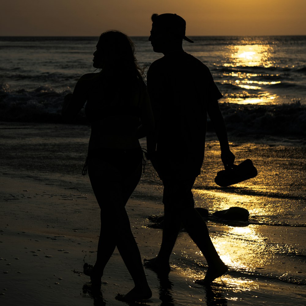 silhouette of couple walking on shore