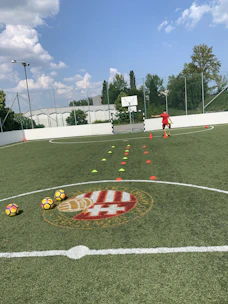 Male football player practicing solo drills with cones in an urban street football setting.