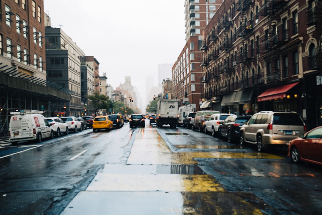 cars parked beside road between buildings