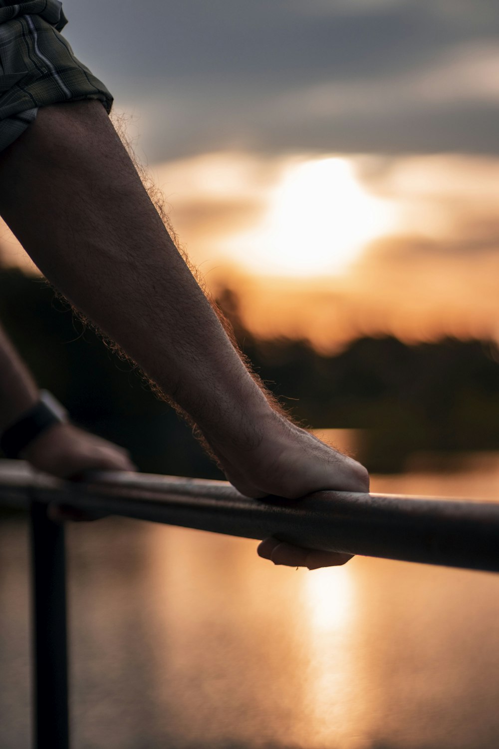 a person standing on a railing with the sun setting in the background
