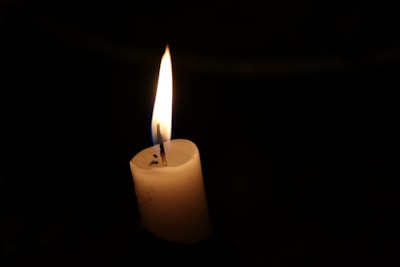 Close-up of a flickering candle flame against a dark, moody background.