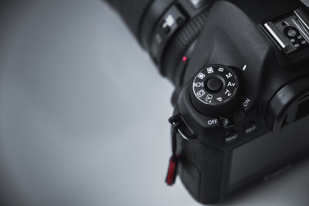 shallow focus photo of black DSLR camera on white surface