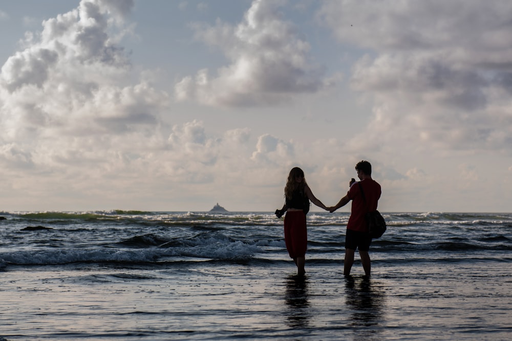 silhouette of two people holding hands at seashore