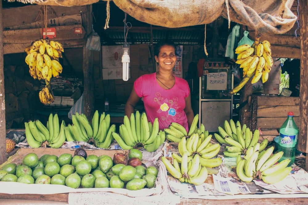 smiling woman standing beside fruit stand