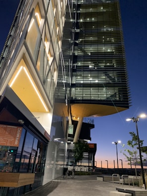 A twilight exterior view of a sleek glass-fronted home reflecting the city skyline, emphasizing sophistication and style.