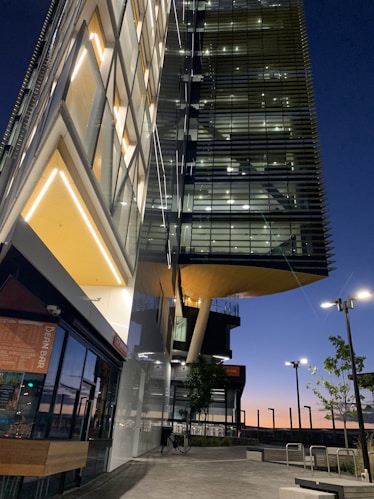 A twilight exterior view of a sleek glass-fronted home reflecting the city skyline, emphasizing sophistication and style.