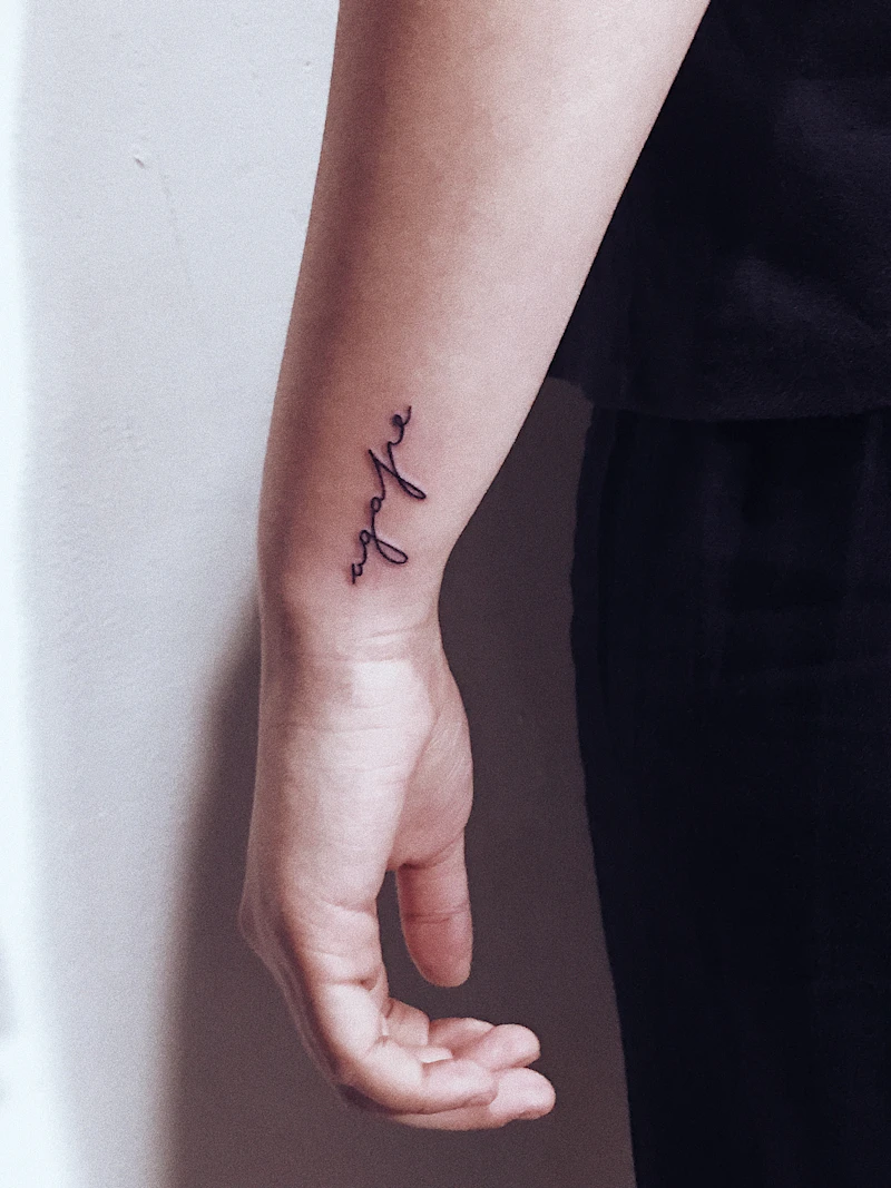 Small, faded script tattoo before refresh