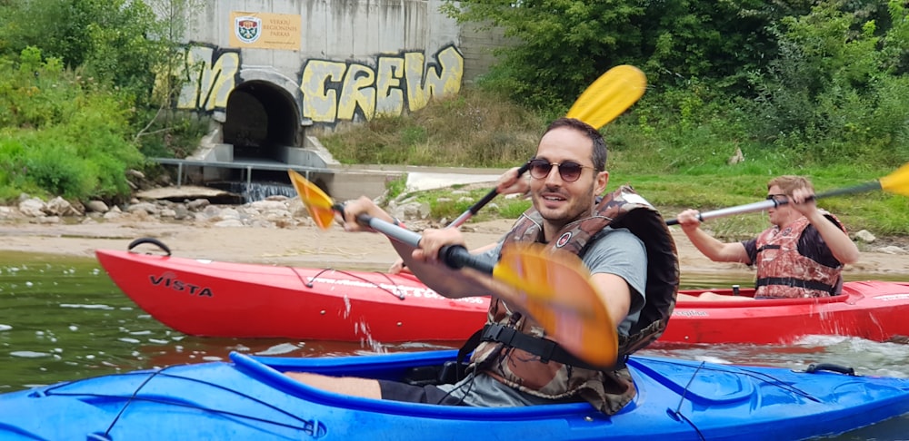 man wearing gray shirt riding blue kayak