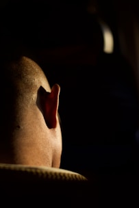 Close-up of a doctor reviewing a patient's scalp under a bright clinical light.