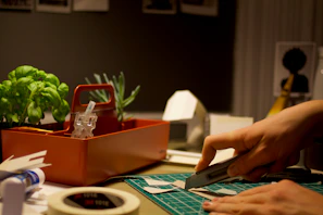 person cutting paper beside orange tray