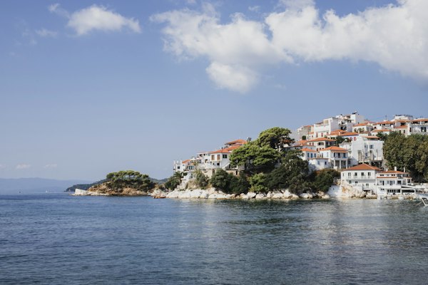 Buildings on island facing body of water under blue sky — Patmos, Greece
