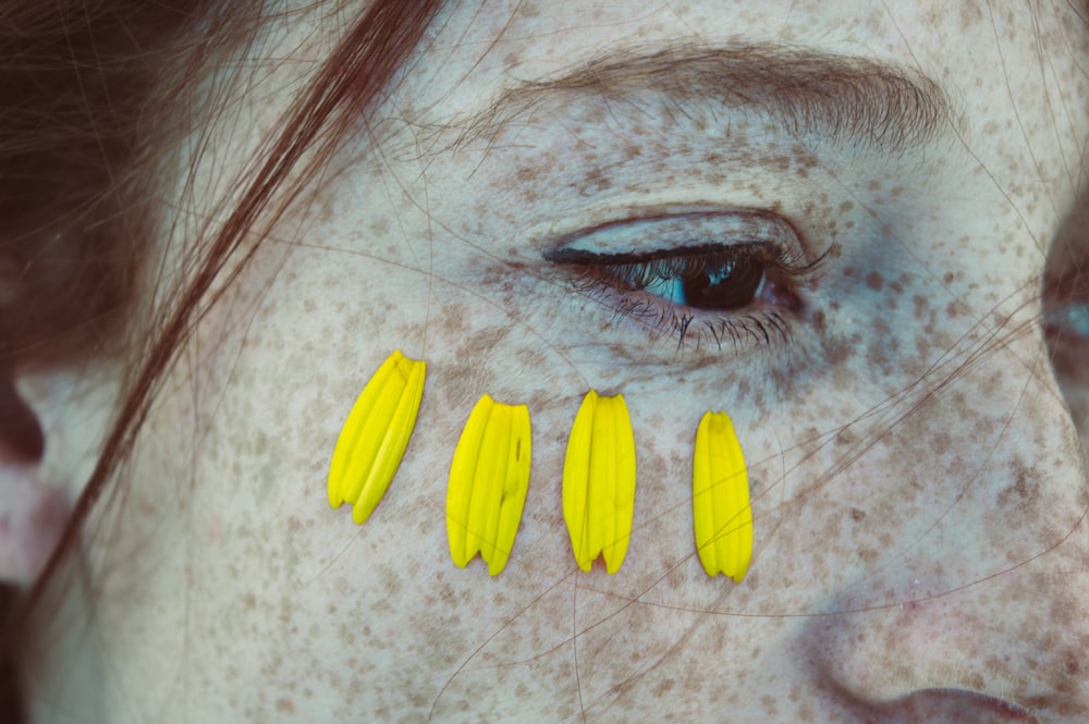 close view of woman's face with four yellow petals